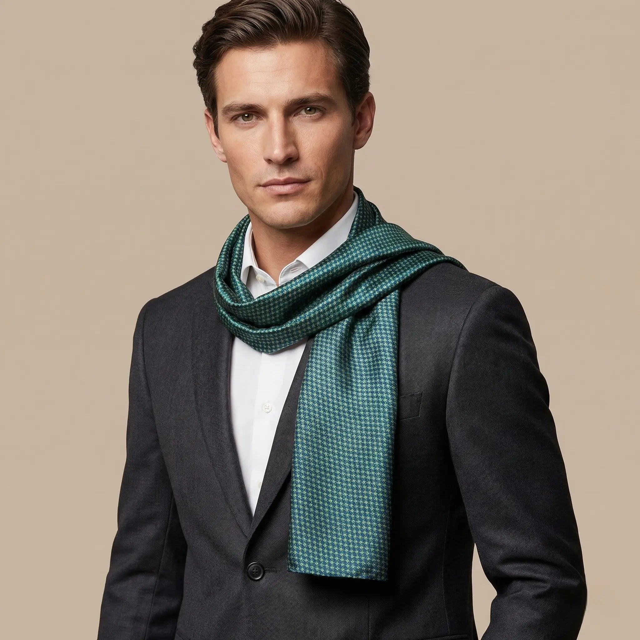 Man wearing a dark suit and green checkered scarf against a beige background