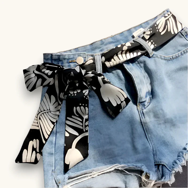 Black and white botanical silk scarf belt tied in bow on denim shorts