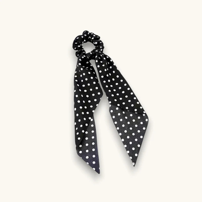 Black bow scrunchie with satin finish, white polka dots, ribbon tail