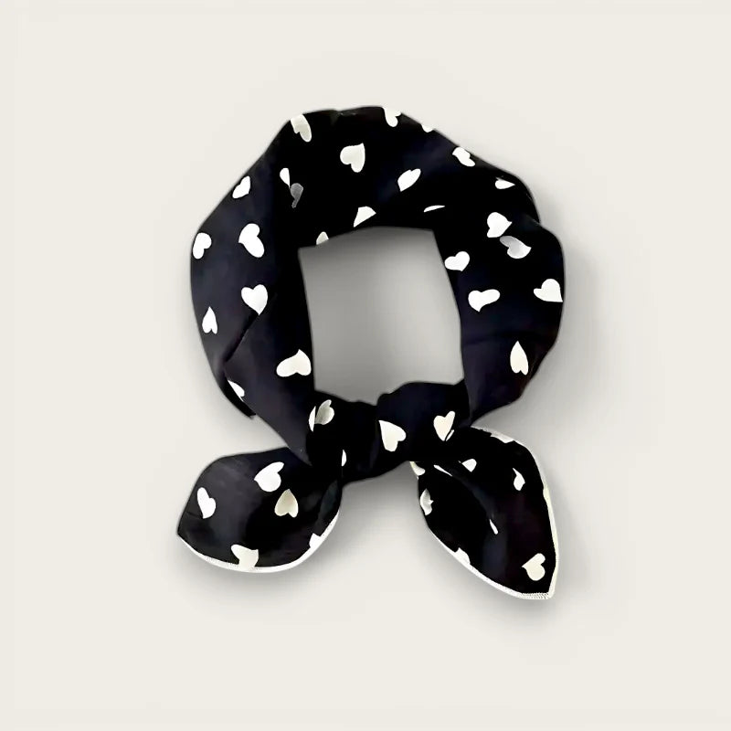Black silk scarf with white heart pattern tied in a knot