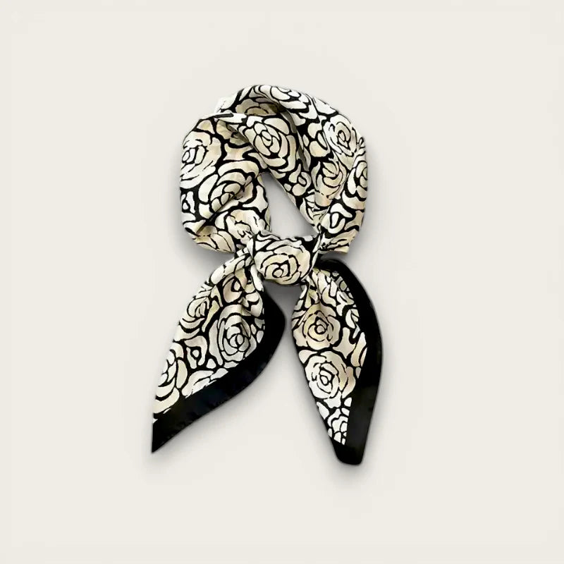 Delicate black and cream rose-patterned silk scarf tied in neat knot