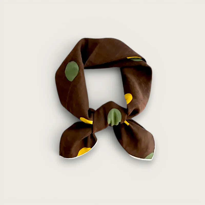 Brown silk scarf with green yellow leaf patterns tied in knot