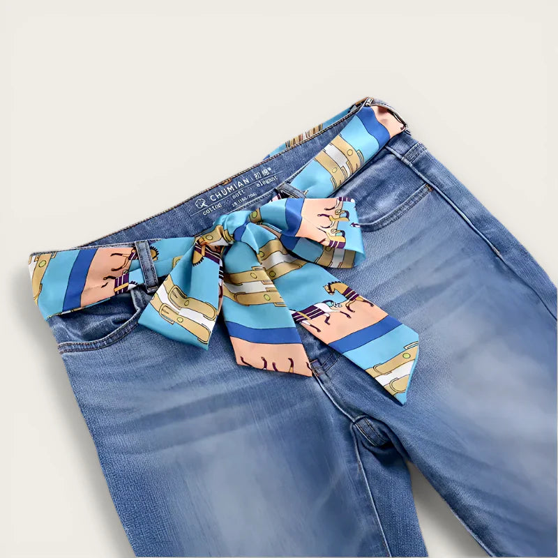 Vibrant blue chiffon scarf belt with cartoon horse pattern tied in bow on jeans