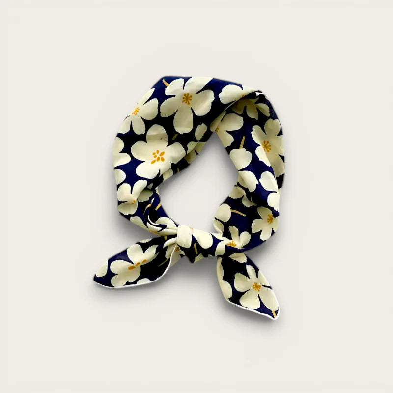 Navy blue silk scarf with white floral pattern, yellow centers, elegant knot