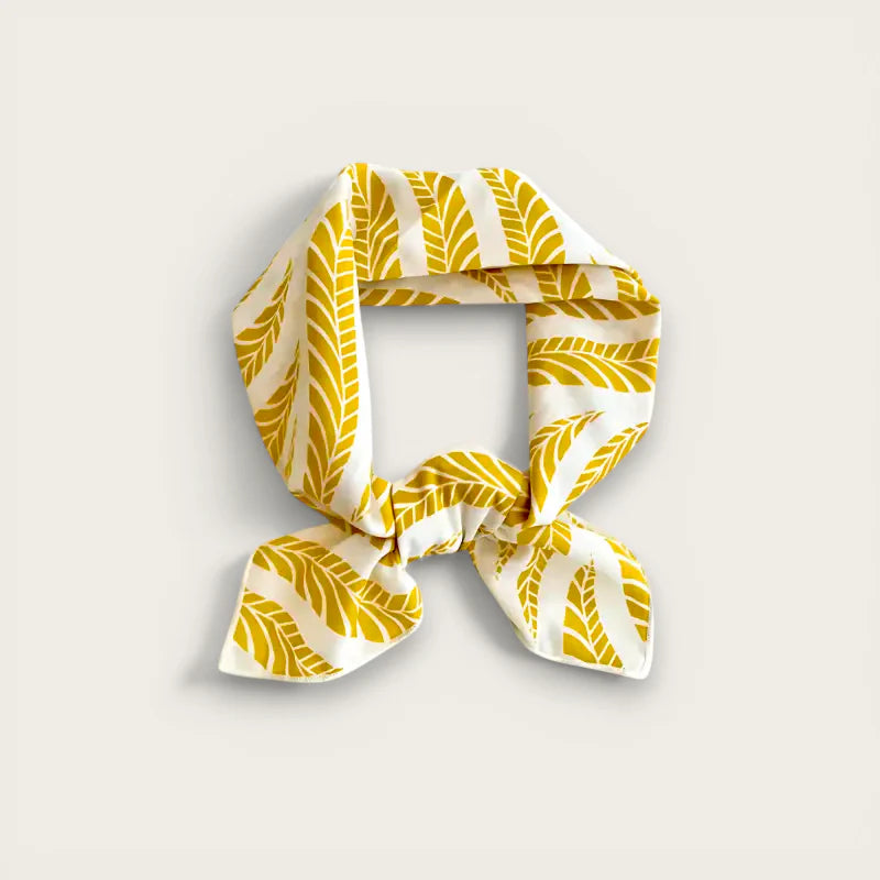 Yellow and white leaf-patterned silk scarf tied in a knot