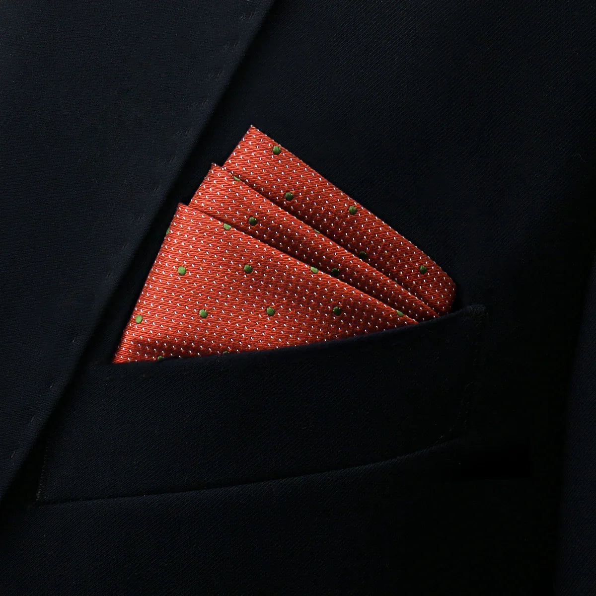 Dark orange pocket square with green dots in suit pocket