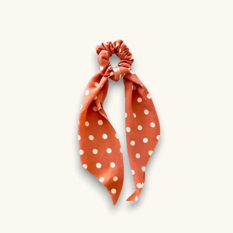 Rust-colored polka dot hair bow scrunchie with tied ribbon design