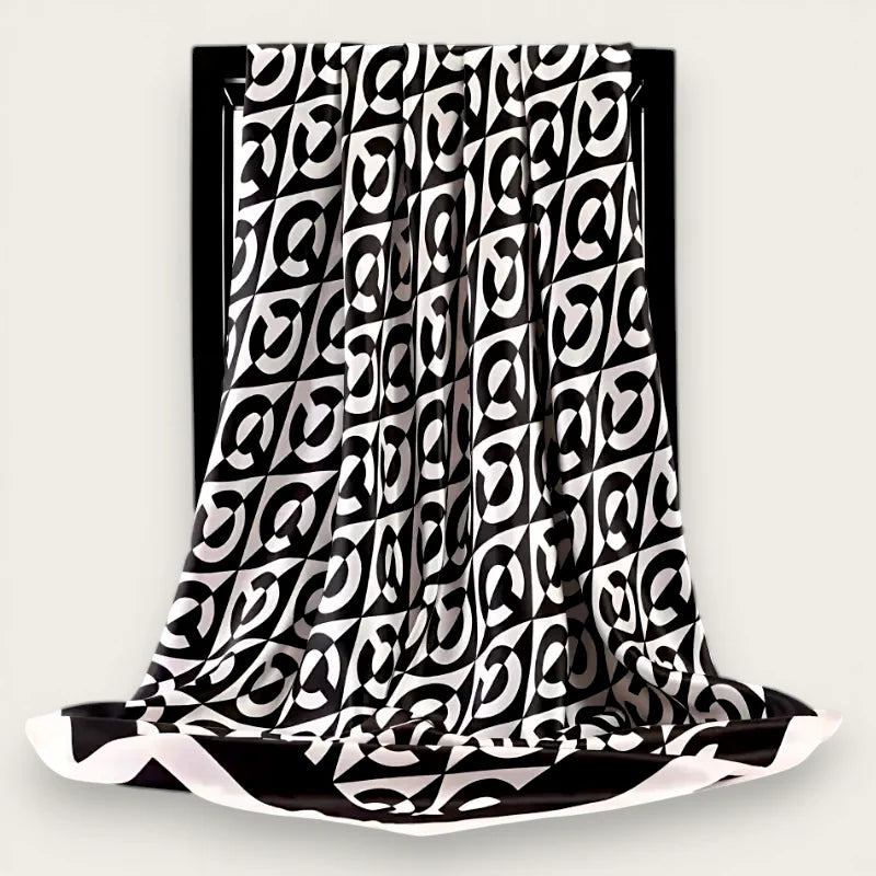 Large black and white geometric silk square scarf draped on black frame