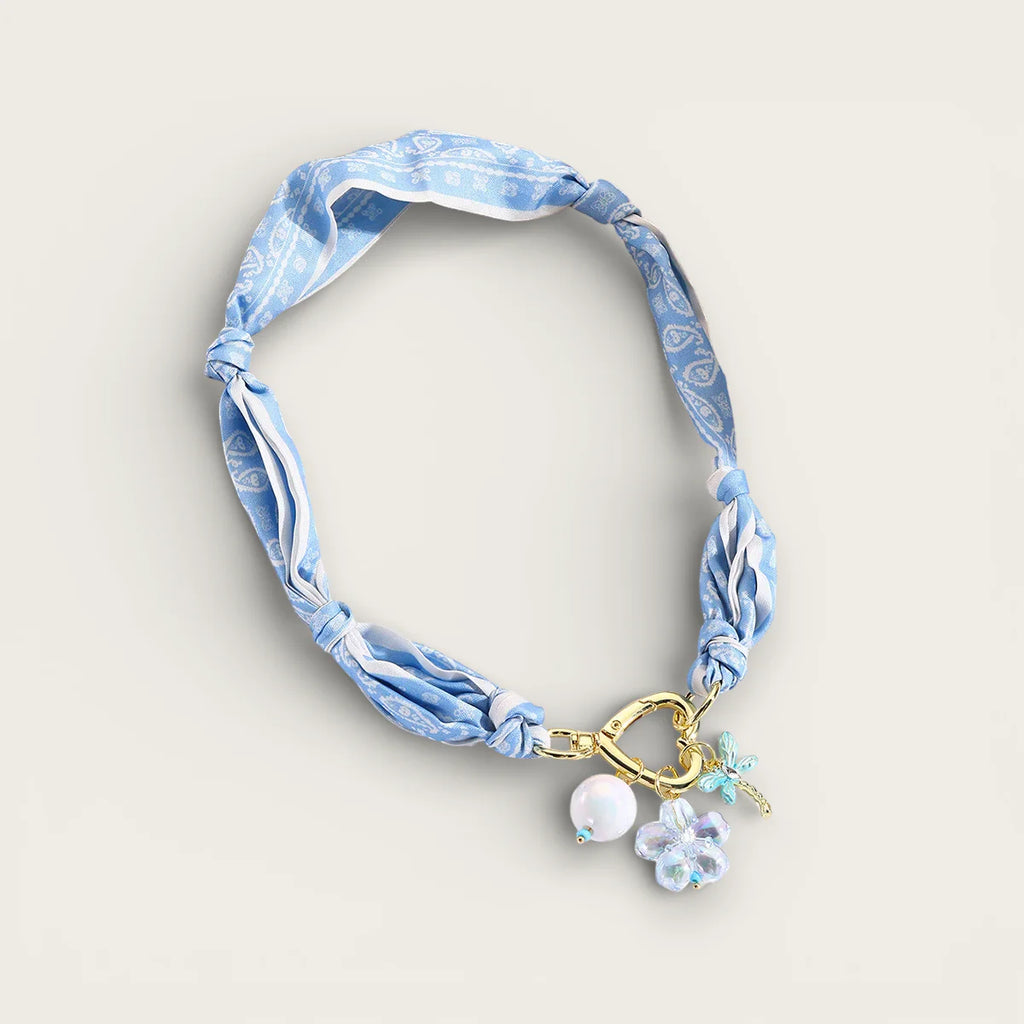 Light blue scarf necklace with knotted pattern, gold clasp, pearl bead, floral charm