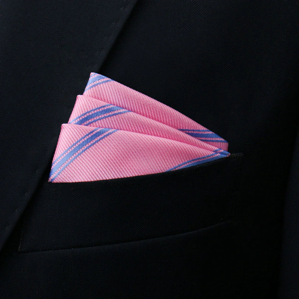 Light pink pocket square in pink-blue stripes folded in black suit pocket