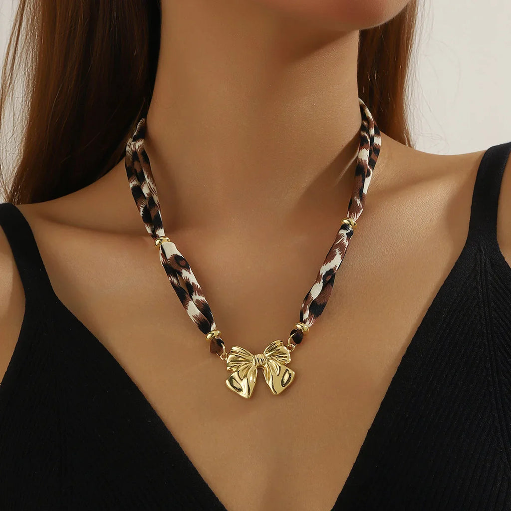 Gold-toned bow pendant on leopard-print cord in Maroon Scarf Necklace