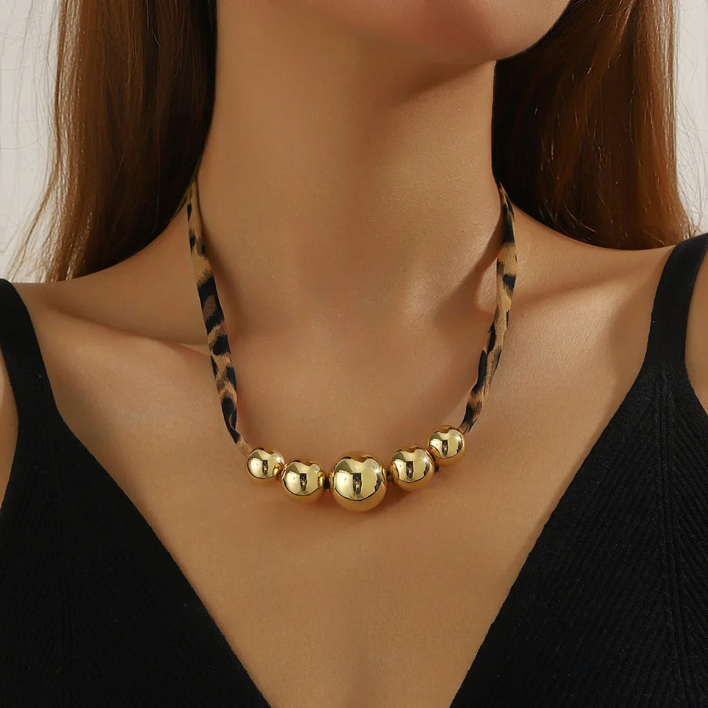 Maroon scarf necklace with gold spherical beads on leopard cord