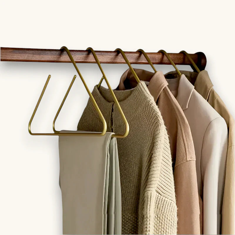 Gold metal scarf hanger with triangular design holding beige cream garments