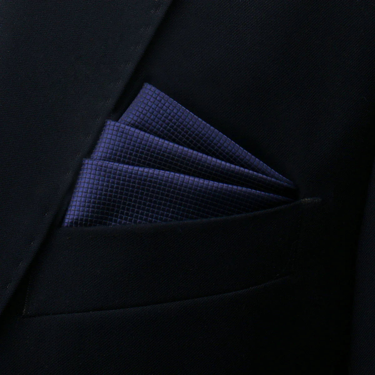 Navy blue pocket square with textured weave in dark suit pocket