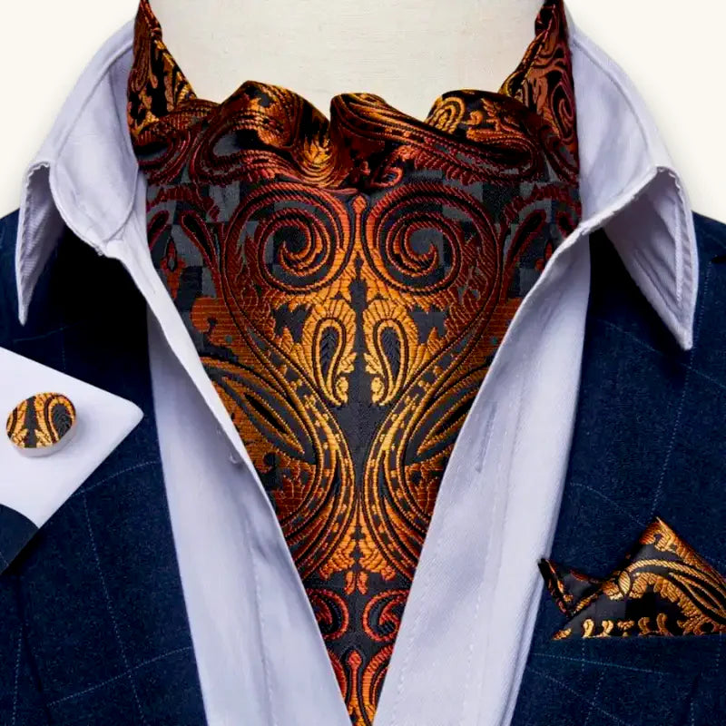 Orange paisley ascot scarf with black patterns on white shirt and navy blazer