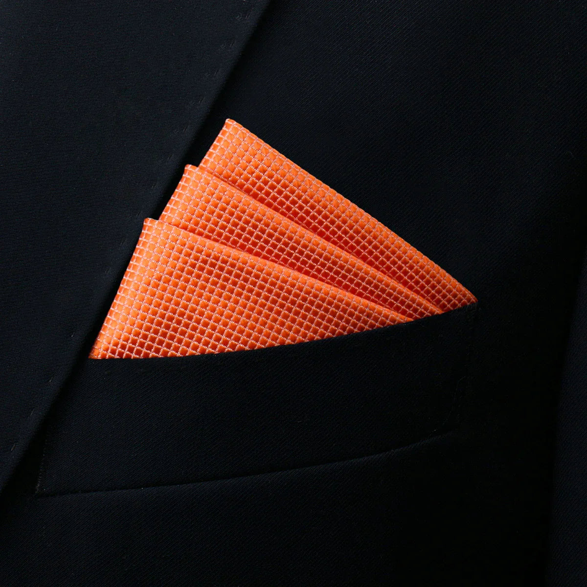 Vibrant orange pocket square with textured weave in black suit pocket