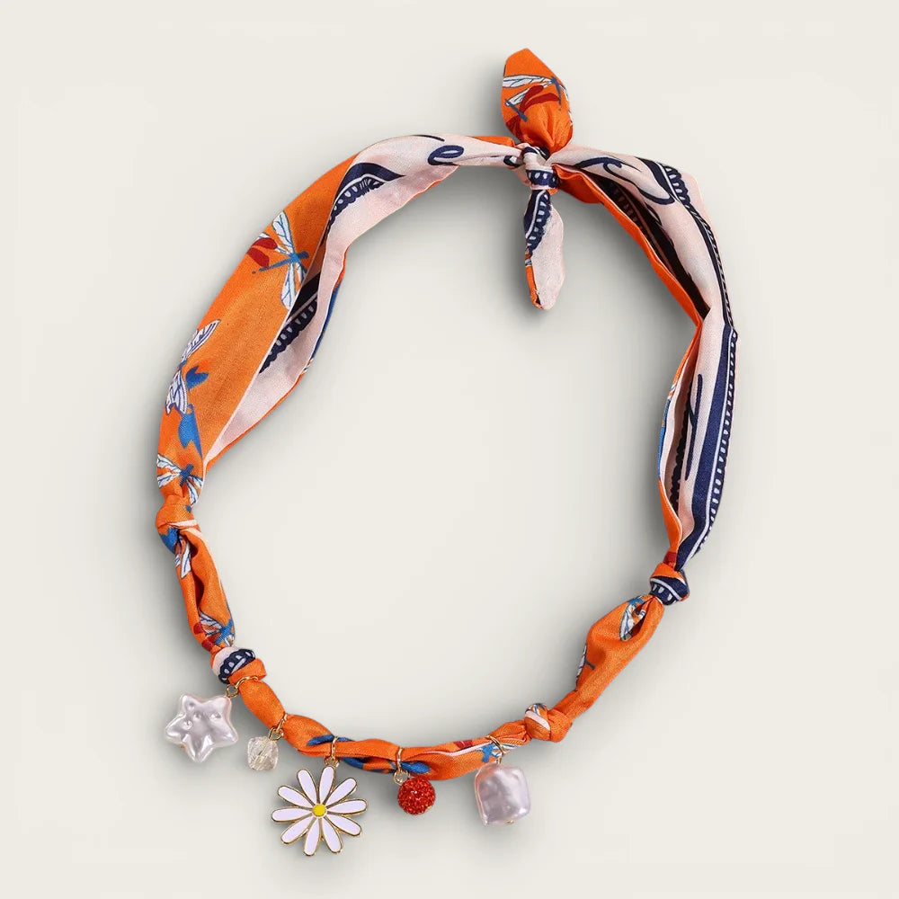 Orange scarf necklace with knotted vibrant print, daisy, star and berry charms