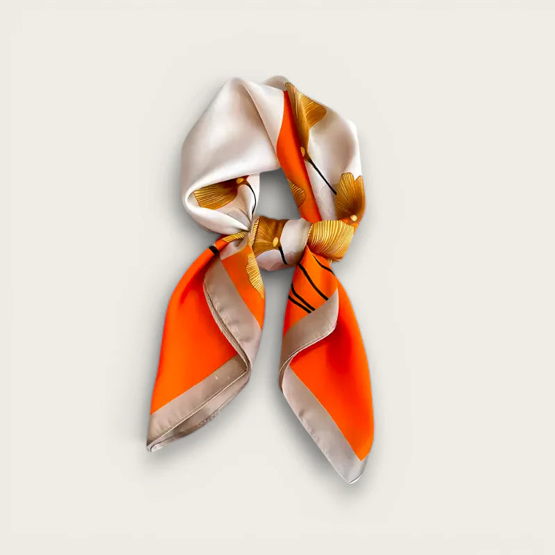 Vibrant orange and cream silk scarf with golden leaf pattern in elegant knot