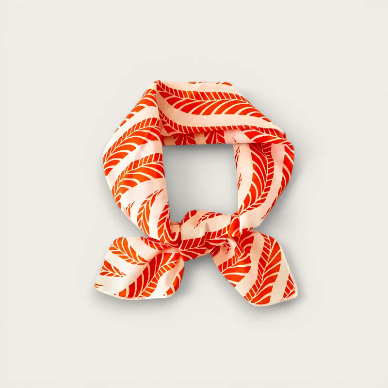 Vibrant orange cream silk scarf with bold leaf pattern in elegant knot