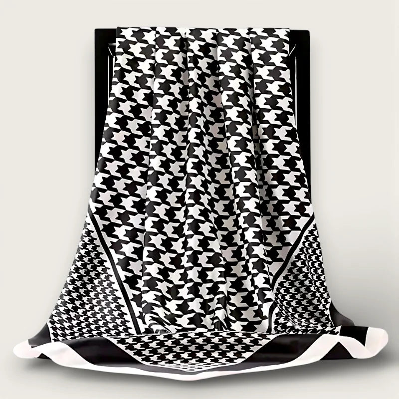 Oversized black and white houndstooth silk scarf draped on black frame