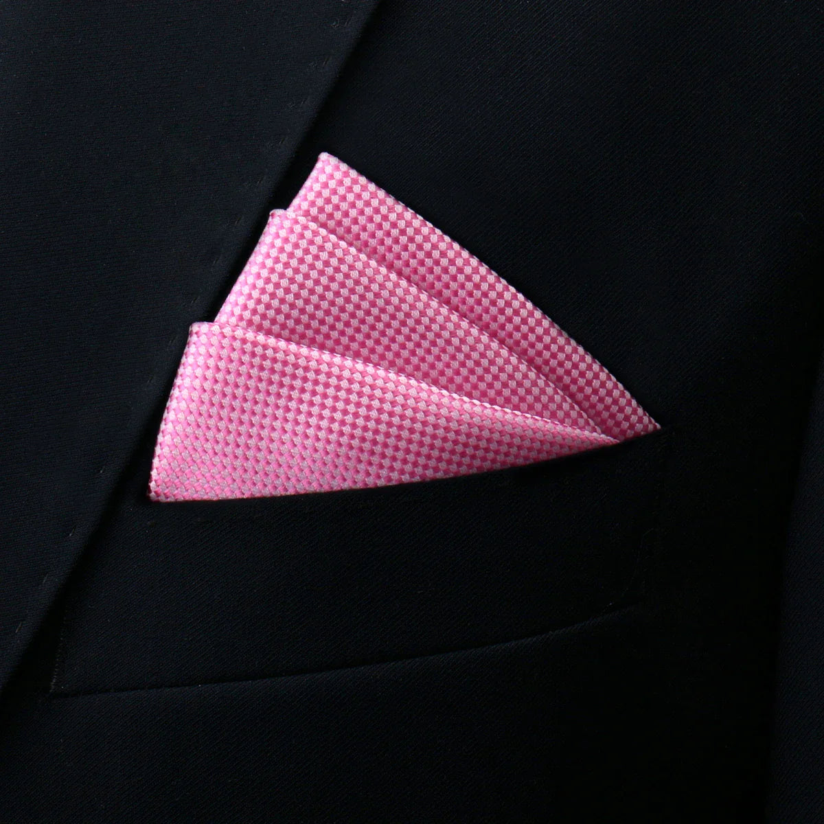 Pink pocket square with subtle checkered pattern in black suit pocket