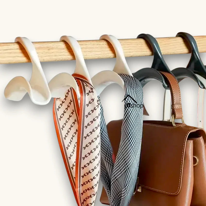 White plastic S-hooks on wooden rod holding patterned scarves and brown leather handbag