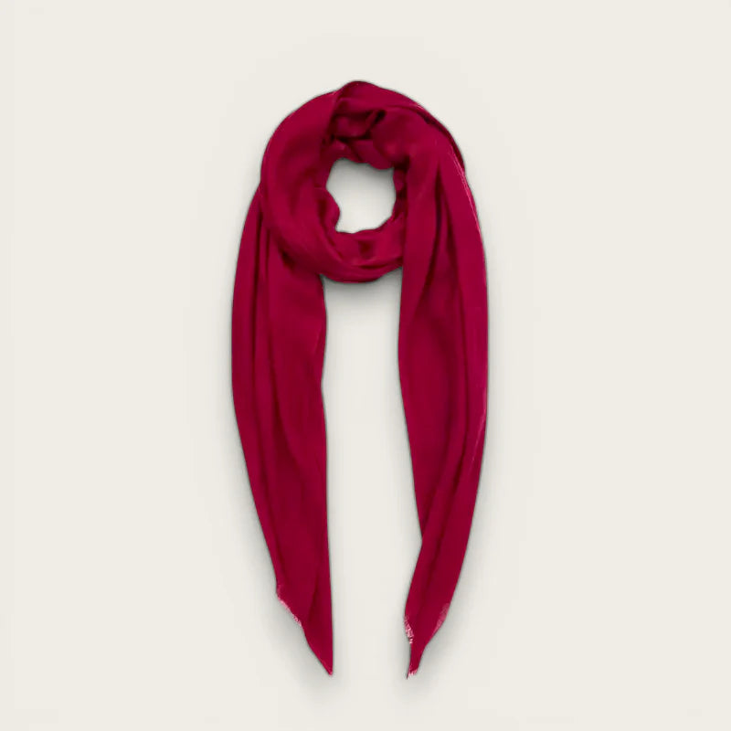 Vibrant fuchsia silk scarf draped elegantly with frayed edges