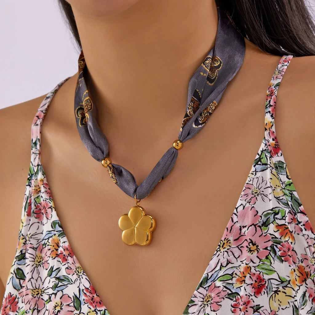 Gold four-leaf clover scarf necklace with gray patterned strap and beads