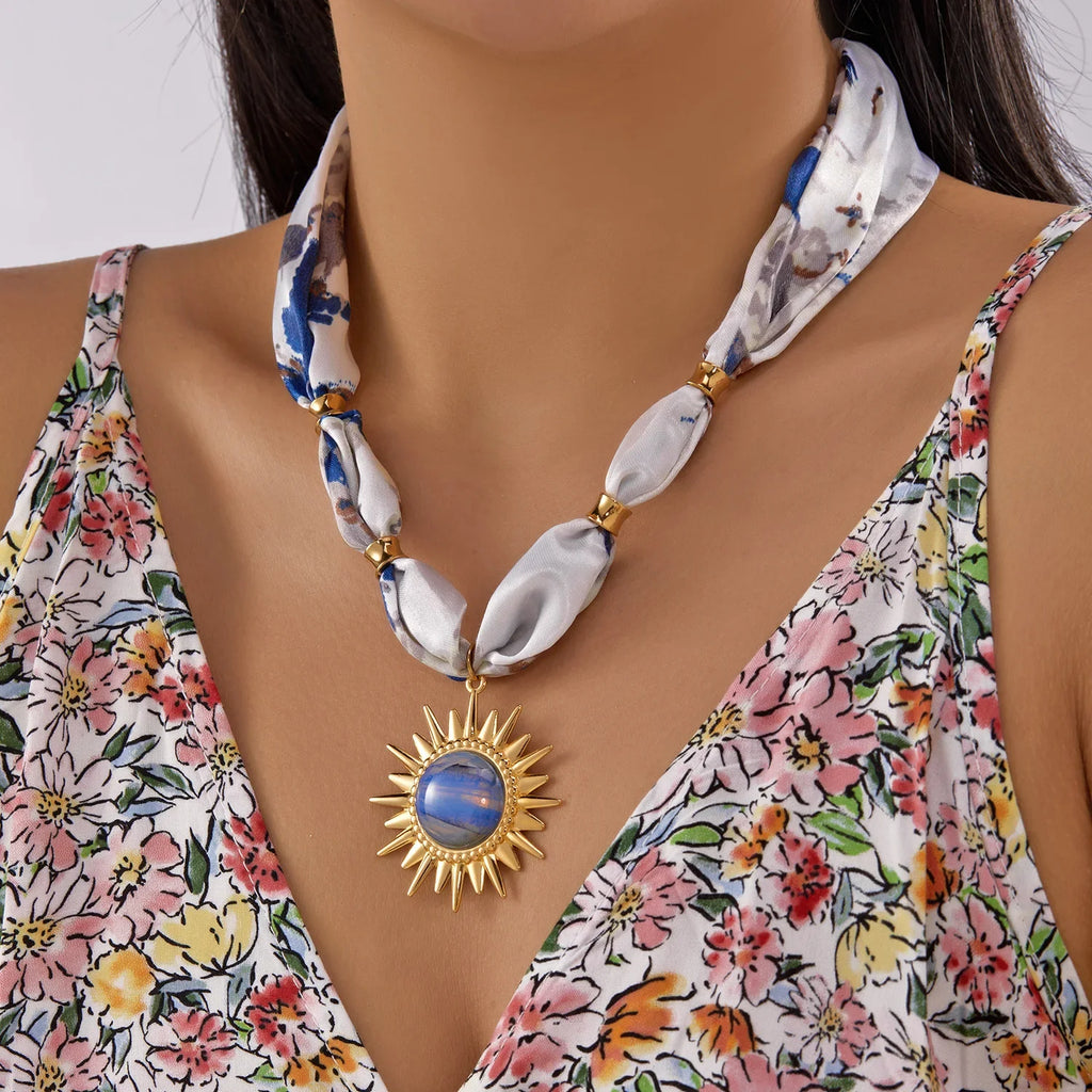 Scarf necklace with gold sunburst charm and blue white marbled stone