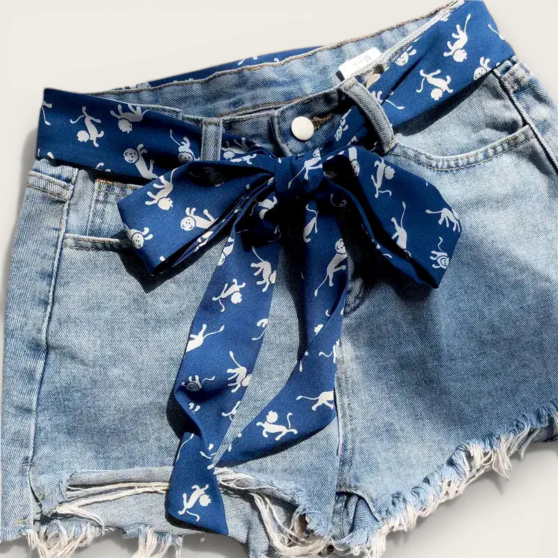 Navy blue silk belt scarf with white monkey prints tied as bow on denim shorts