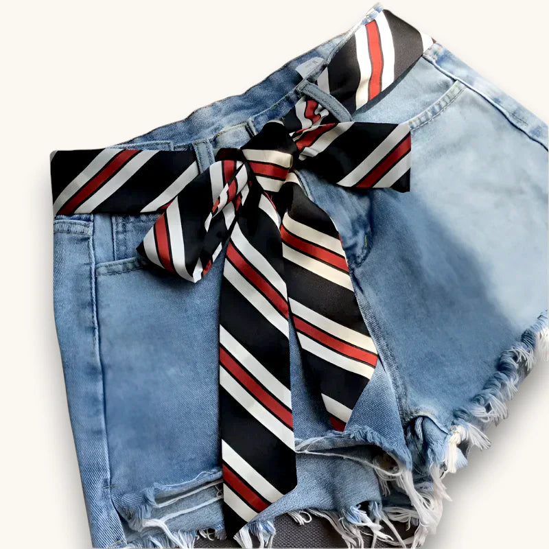 Silk scarf belt with black white red stripes tied as bow on denim shorts