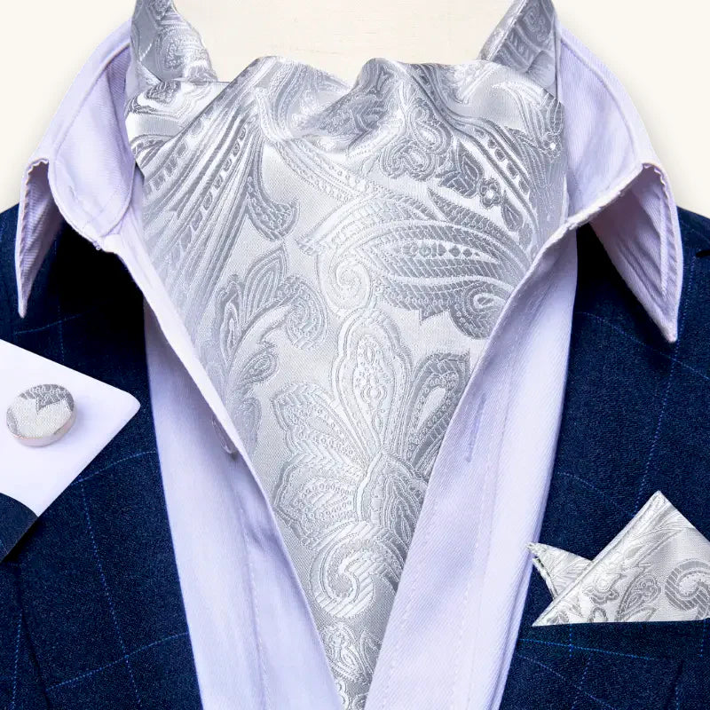 Silver paisley ascot tie with woven pattern on lavender shirt and navy suit