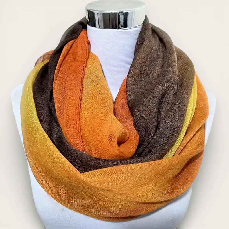 Warm infinity scarf in orange, mustard yellow, and brown on mannequin