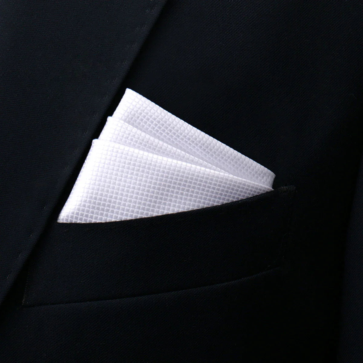 White pocket square with textured weave in black suit pocket