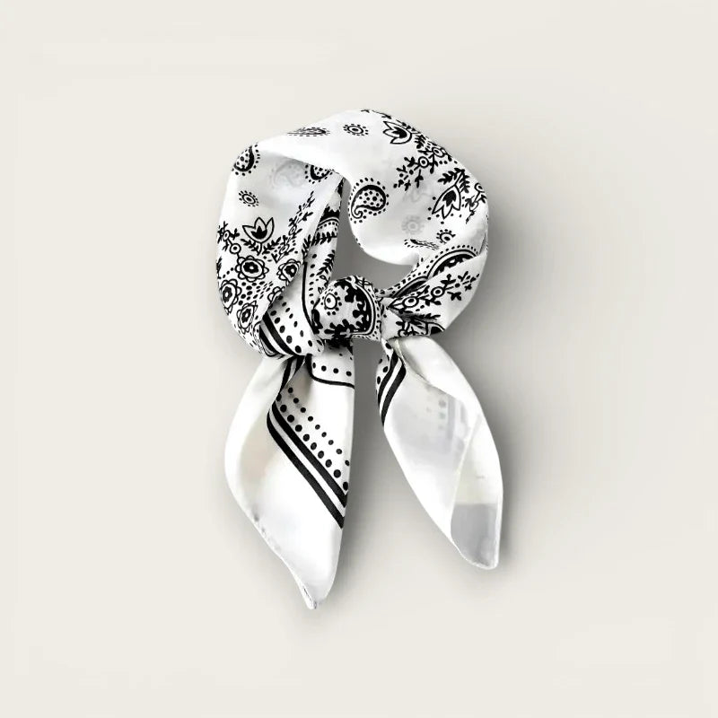 White silk scarf with black paisley floral pattern tied in knot
