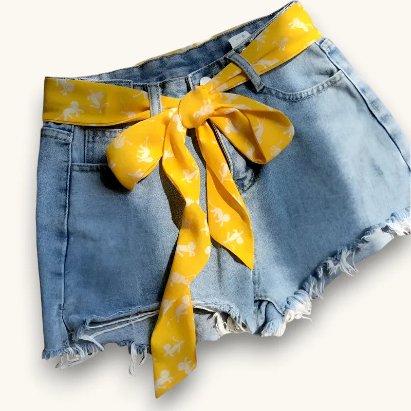 Light-wash denim shorts with frayed hem and yellow scarf belt with white horse silhouettes